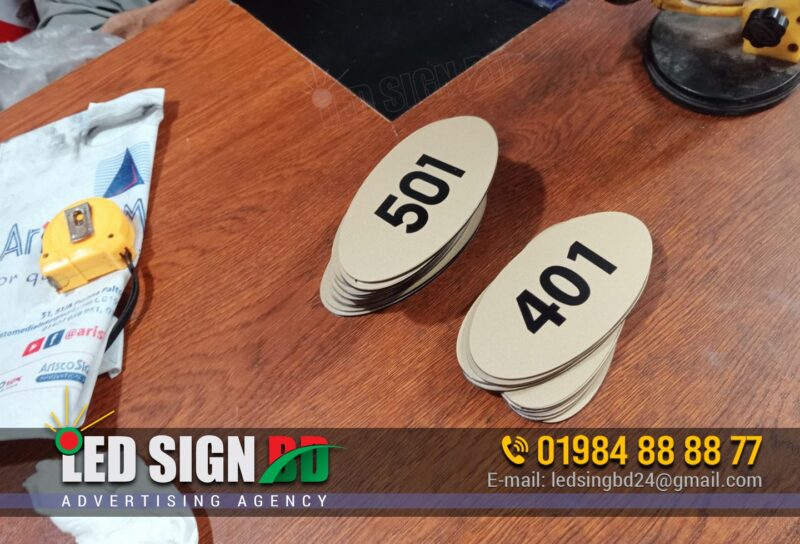 ACP Board UV Printing Door Name Plate Maker BD, Digital LED Outdoor and Indoor Nameplate Signage Bangladesh, Door Signage directional nameplate, Door number plate, Doctor Romm Number plate, Plastic Door nameplate design and maker in Bangladesh. Different Types of Door Name Plates Acrylic Name Plate, Stainless Steel (SS) Name Plate, Brass Name Plate, Wooden Name Plate, Glass Name Plate, PVC or Plastic Name Plate, Marble or Stone Name Plate, Engraved Name Plate, Printed Name Plate, LED Backlit Name Plate, Great for visibility at night, 3D Letter Name Plate, Customized Themed Name Plate, Front Door Name Plate, Wall-Mounted Name Plate, Hanging Name Plate, Residential Name Plates, Office Door Name Plates, Business/Shop Name Plates.