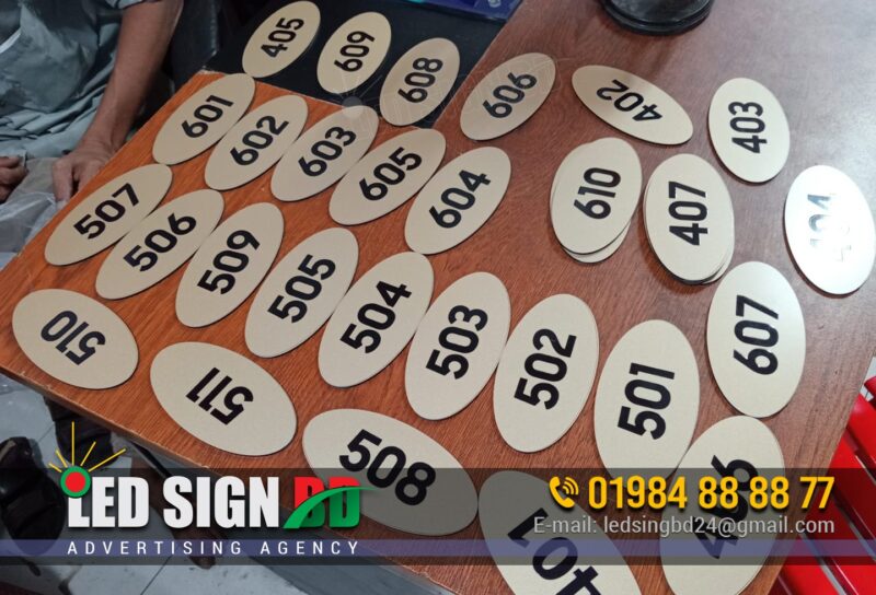 ACP Board UV Printing Door Name Plate Maker BD, Digital LED Outdoor and Indoor Nameplate Signage Bangladesh, Door Signage directional nameplate, Door number plate, Doctor Romm Number plate, Plastic Door nameplate design and maker in Bangladesh. Different Types of Door Name Plates Acrylic Name Plate, Stainless Steel (SS) Name Plate, Brass Name Plate, Wooden Name Plate, Glass Name Plate, PVC or Plastic Name Plate, Marble or Stone Name Plate, Engraved Name Plate, Printed Name Plate, LED Backlit Name Plate, Great for visibility at night, 3D Letter Name Plate, Customized Themed Name Plate, Front Door Name Plate, Wall-Mounted Name Plate, Hanging Name Plate, Residential Name Plates, Office Door Name Plates, Business/Shop Name Plates.