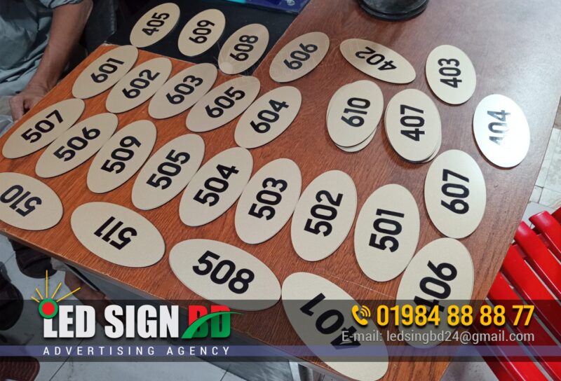 ACP Board UV Printing Door Name Plate Maker BD, Digital LED Outdoor and Indoor Nameplate Signage Bangladesh, Door Signage directional nameplate, Door number plate, Doctor Romm Number plate, Plastic Door nameplate design and maker in Bangladesh. Different Types of Door Name Plates Acrylic Name Plate, Stainless Steel (SS) Name Plate, Brass Name Plate, Wooden Name Plate, Glass Name Plate, PVC or Plastic Name Plate, Marble or Stone Name Plate, Engraved Name Plate, Printed Name Plate, LED Backlit Name Plate, Great for visibility at night, 3D Letter Name Plate, Customized Themed Name Plate, Front Door Name Plate, Wall-Mounted Name Plate, Hanging Name Plate, Residential Name Plates, Office Door Name Plates, Business/Shop Name Plates.